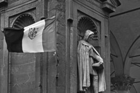 saint and flag on the facade of a building in florence