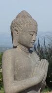 gray statue of a praying Buddha in Asia