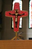 bronze Jesus figure on red Cross, crucifixion