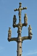 gothic stone Cross with Crucifixion and figures of saints at sky, france, brittany