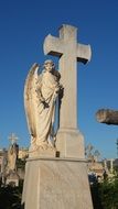 angel near the cross like a statue in a cemetery