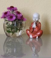 figurine of a little buddha and flowers on a glass table