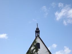 cross and bell on roof of church at sky