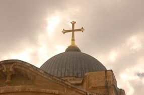 golden cross on christian temple against gray sky