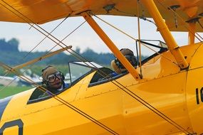 yellow Oldtimer Aircraft with two persons on desk Taking Off