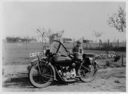 black and white photo of a child on an old motorcycle with a sidecar