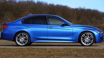 side view of a luxurios blue car near the trees