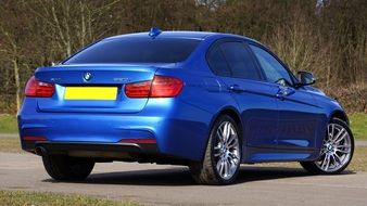 rear view of a luxury blue BMW on a sunny day