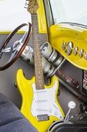 yellow guitar in the interior of a yellow vintage car