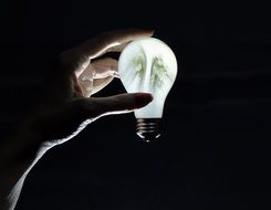 glowing light bulb in hand in the dark