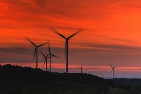 wind turbines against a bright orange sunset