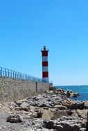 striped red-white lighthouse on the edge of the promenade