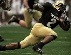 American football player carries the ball across the field