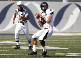 player with ball in white uniform and referee in american football