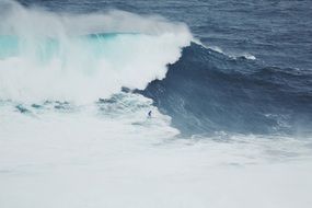 distant view of a surfer in powerful white waves
