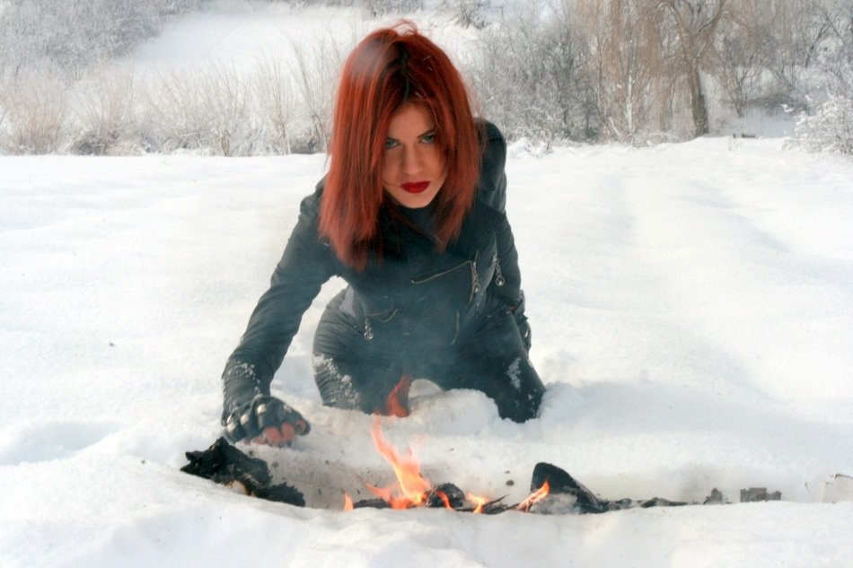 beautiful girl with red lips near a fire in the snow