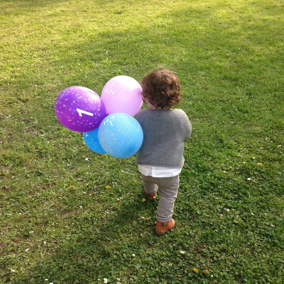 little child with colorful balloons on the lawn