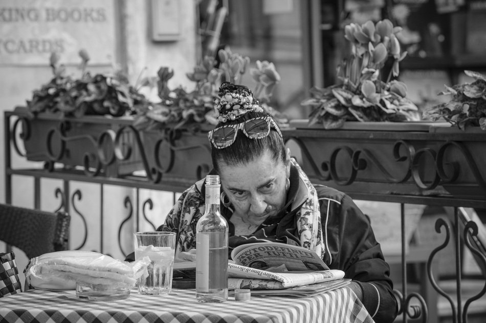 senior woman Reading newspeper at table, Italy, Rome, Piazza Navona