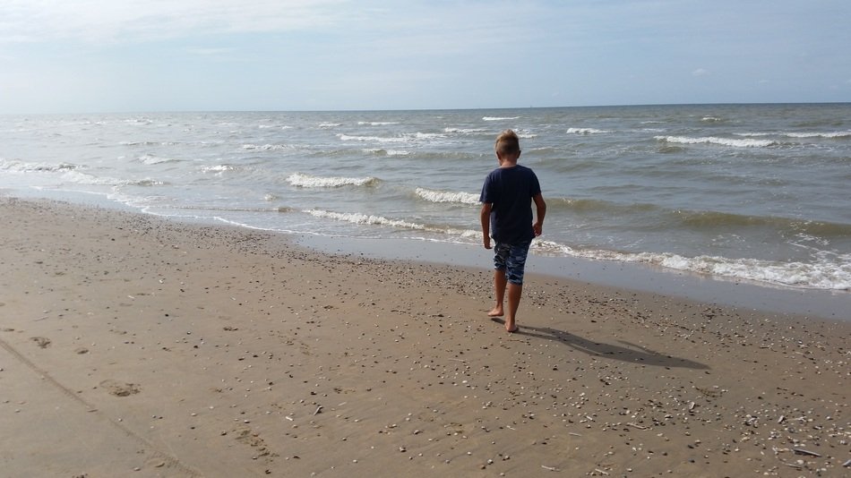 a boy walks along the seashore in Holland