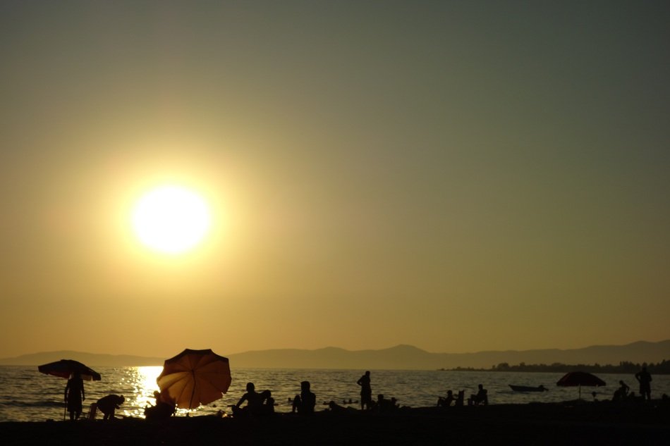 people on the beach near the water during sunset