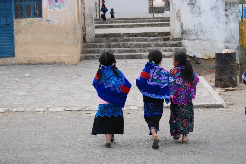 three mexican little girls walking down the street in textiles