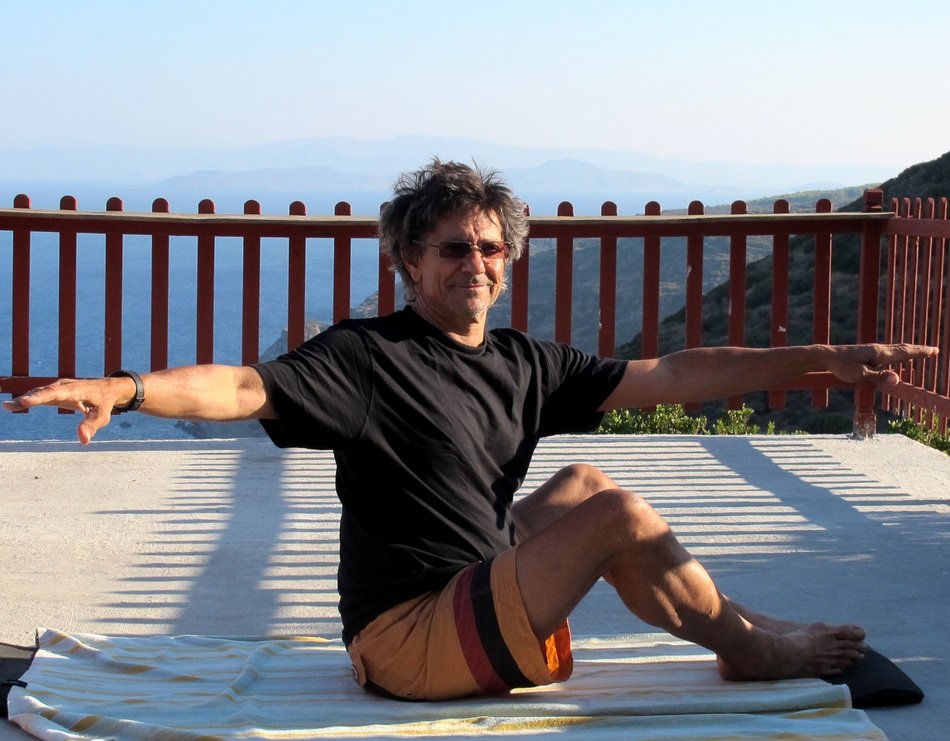 Male doing yoga on the coast at the sunrise