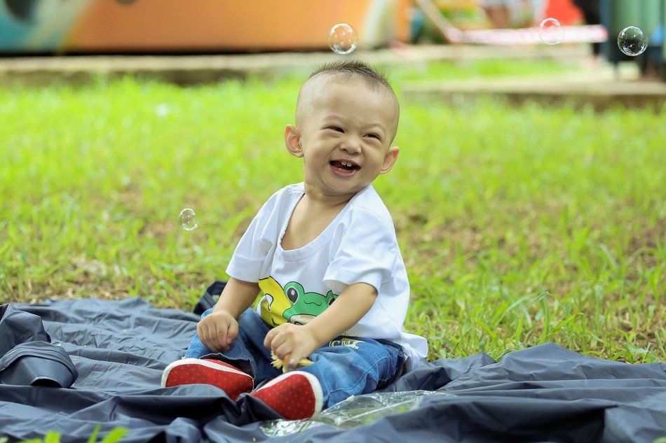 asian baby boy plays with soap bubbles