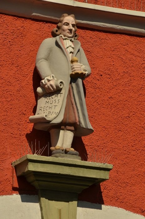 stone sculpture of a man on a red background