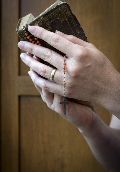 prayer book and rosary in hands close-up