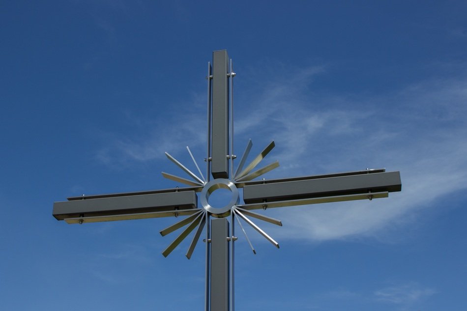 metal christian cross against a clear blue sky