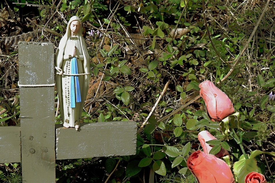 Madonna figurine on the cross in the cemetery
