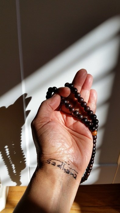 the hand of the man with the beads at the window