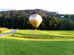 golden Hot Air Balloon above farmland at summer evening