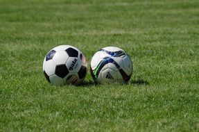 Close-up of the two colorful soccer balls on green grass