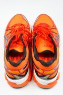 Back view of the sneakers of a neon orange color on white background