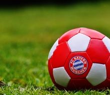 red soccer ball on green grass closeup
