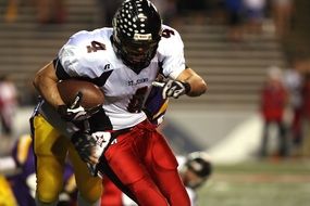 player in helmet with ball in american football