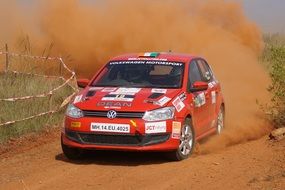 red racing car on a dusty rally track in india