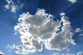 illuminated white fluffy clouds on the blue sky