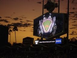 baseball stadium with big screen at dusk