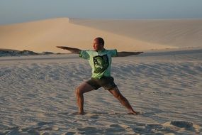 A man doing yoga on the white sand