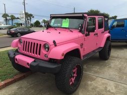 pink jeep is parked on the street