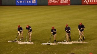 photo of humans cleaning baseball field