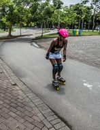 girl in pink helmet roller skates in the park