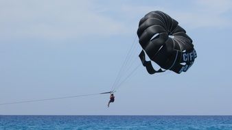 black parachute of a paraglider above the water