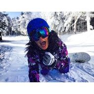 girl in a winter suit and mountain glasses lies on a snowy slope