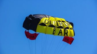 yellow blue parachute on the blue sky