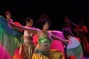 group of oriental dancers in multi-colored dresses