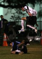 soccer player jumps over a player