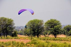 landscape of A man on a parachute landed near the green trees
